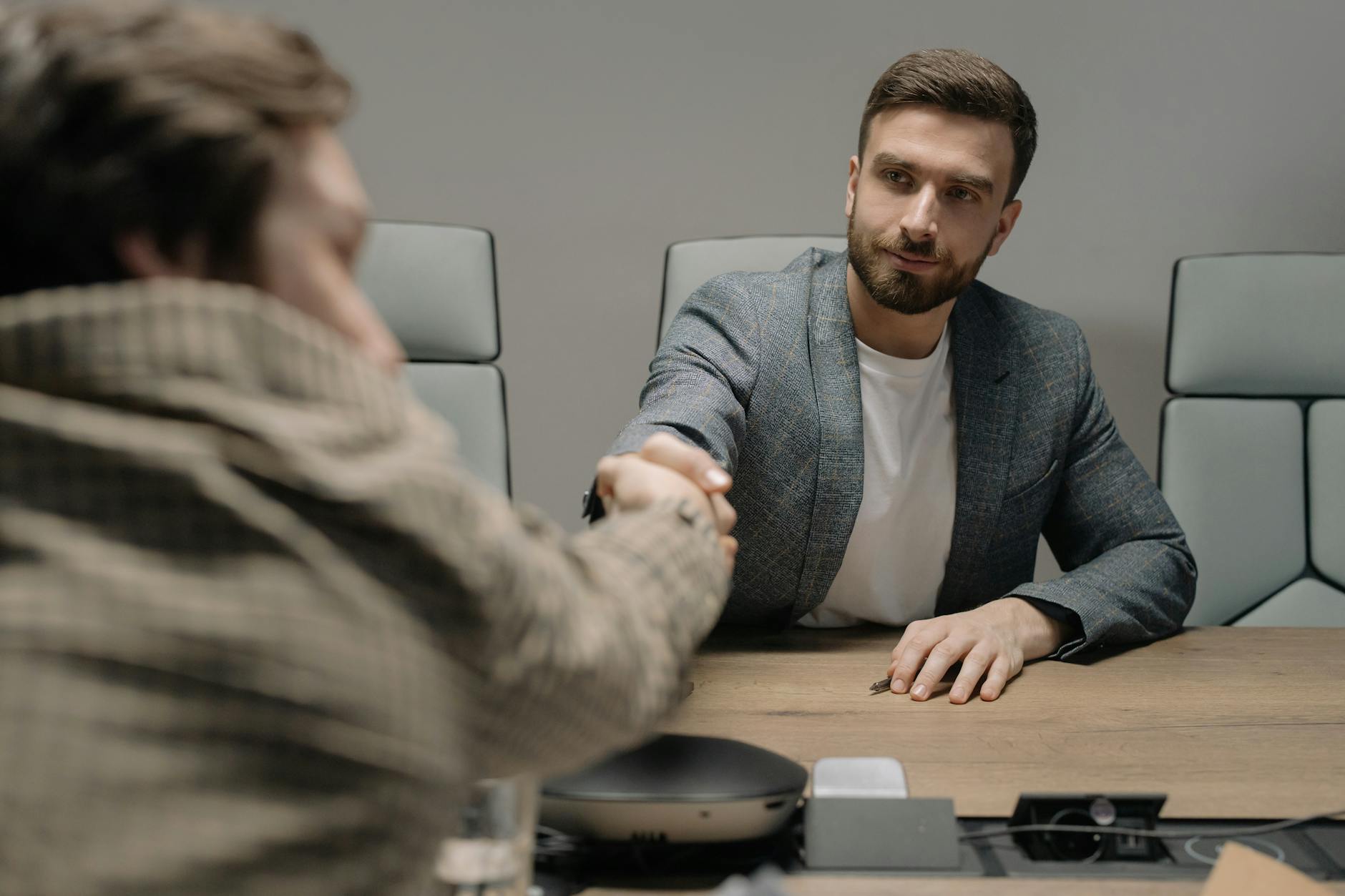 Professional handshake between two people in a modern office
